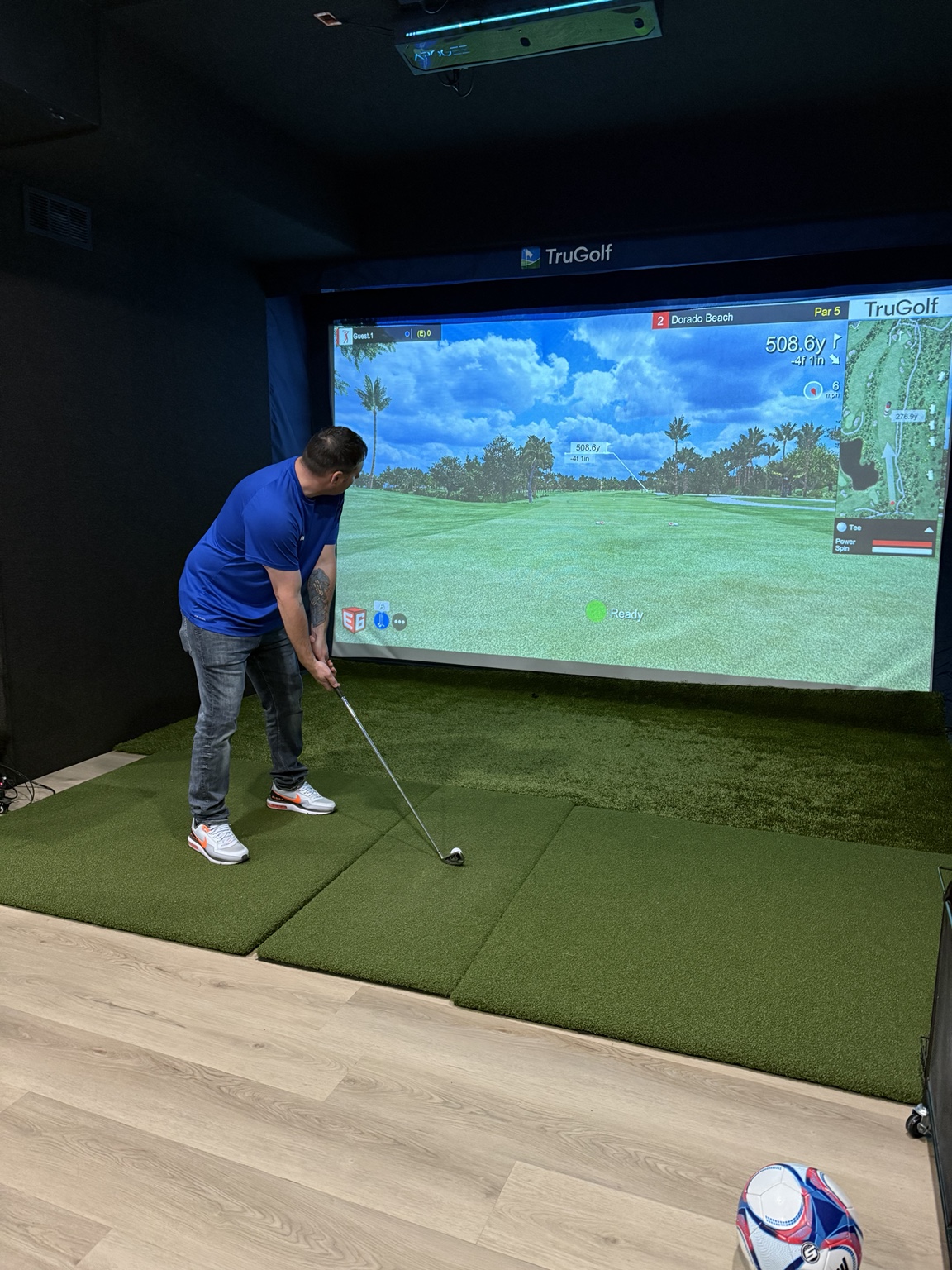 A golfer playing in Triple Play Sports’ TruGolf simulator bay